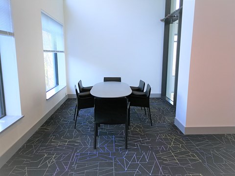 A conference room with a table surrounded by chairs.
