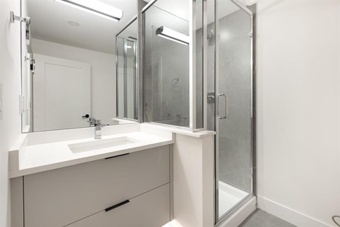 A white bathroom vanity with a sink and mirror.