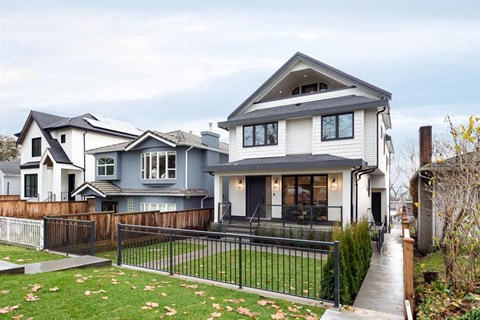 A modern house with a grey and white exterior and a black fence.