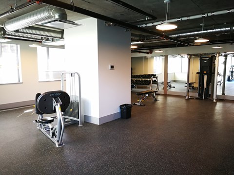 A gym with a weight bench and a black bag on the floor.