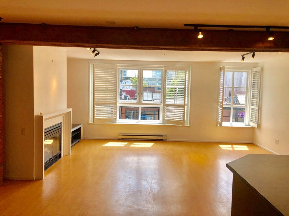 an empty living room with a fireplace and windows