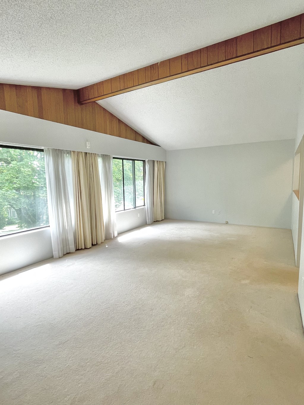 an empty living room with a large window and curtains