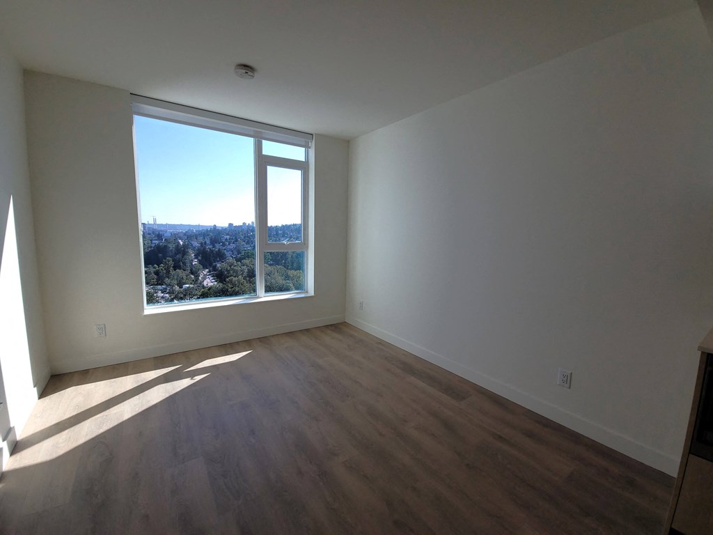 an empty living room with wooden floors and a window
