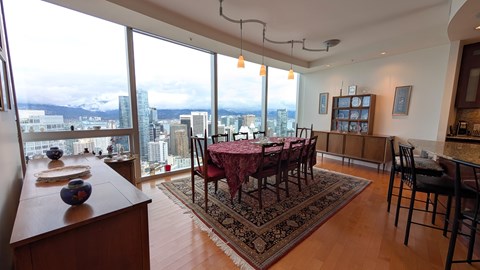 A dining room with a table set for a meal and a view of the city.