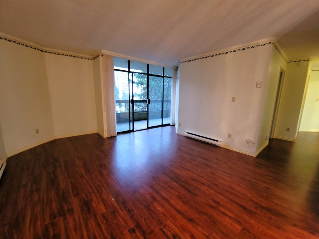an empty living room with hardwood floors and white walls