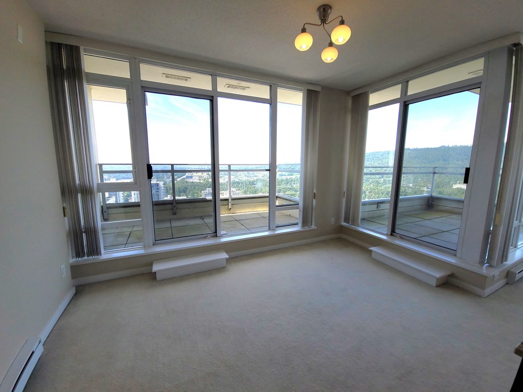 an empty living room with large windows and a carpet