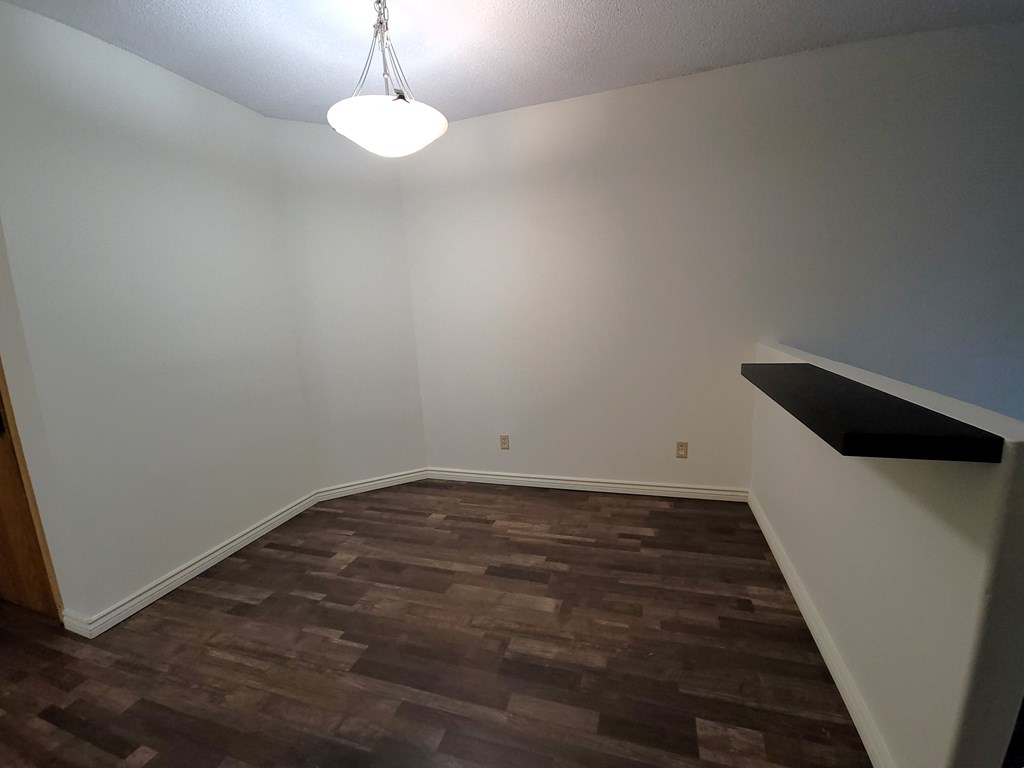 a empty living room with wood flooring and white walls