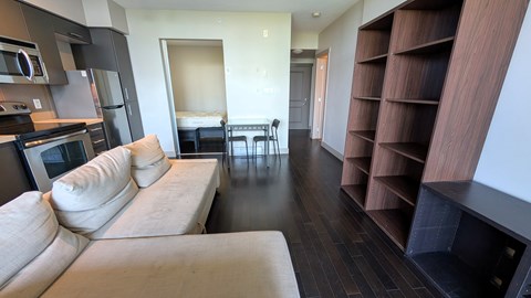 A modern living room with a white couch and a wooden bookshelf.