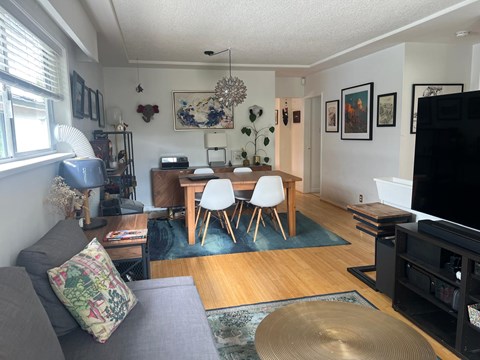 A living room with a grey couch and a wooden dining table.