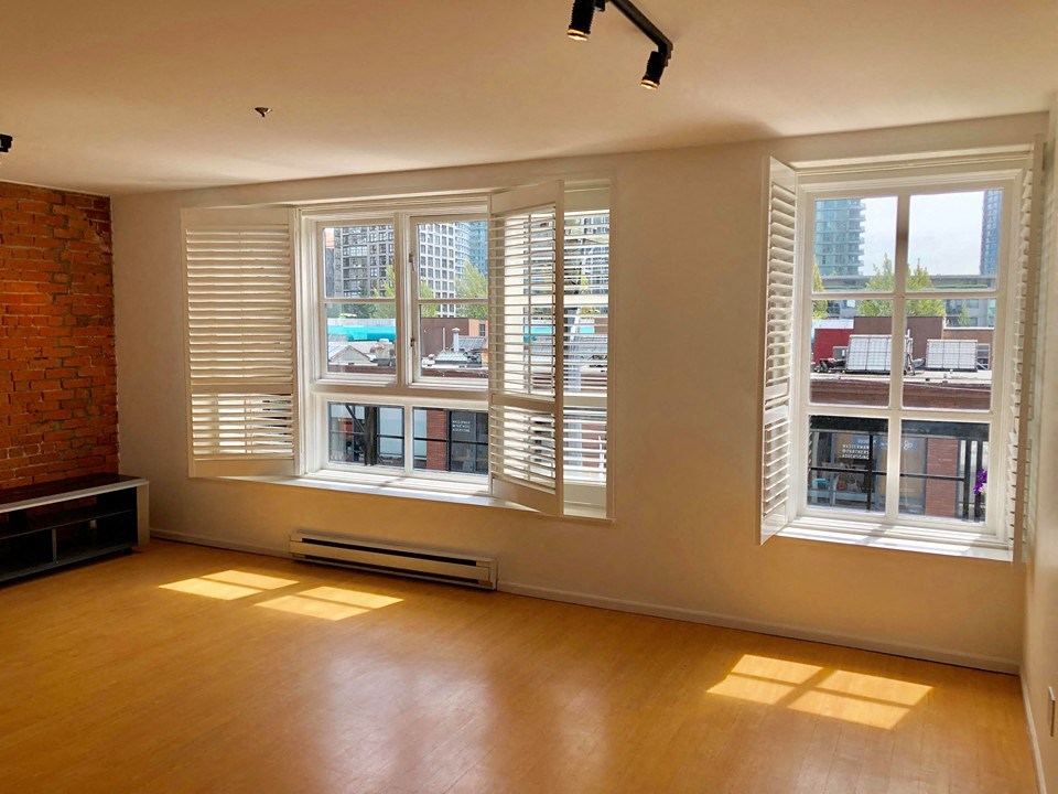 an empty living room with large windows and wood floors