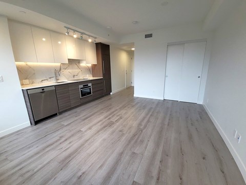 A spacious room with a kitchen area and a door to another room.