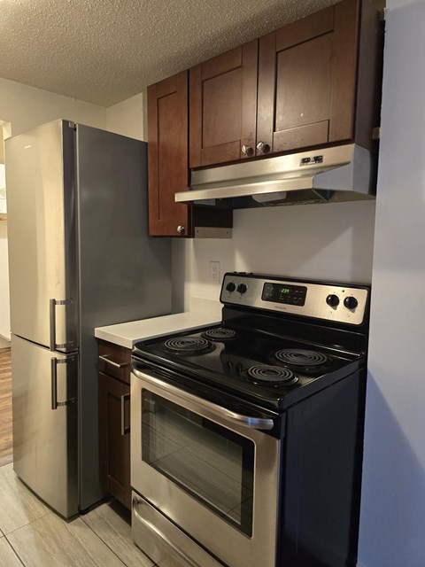 A modern kitchen with a stainless steel refrigerator and oven.