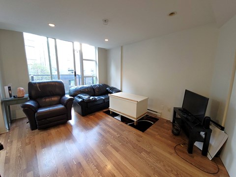 A living room with a black leather chair and a black leather couch.