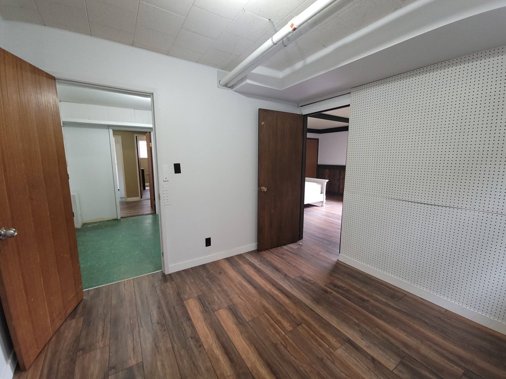 a view of a living room and a hallway with wood flooring and a door