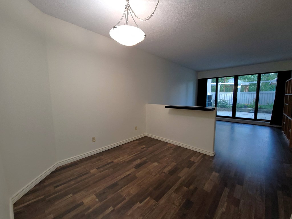 an empty living room with wood flooring and a window