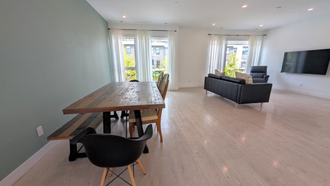A modern living room with a wooden dining table and chairs.