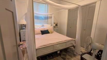 A small bedroom with a bed, nightstand, and fan.
