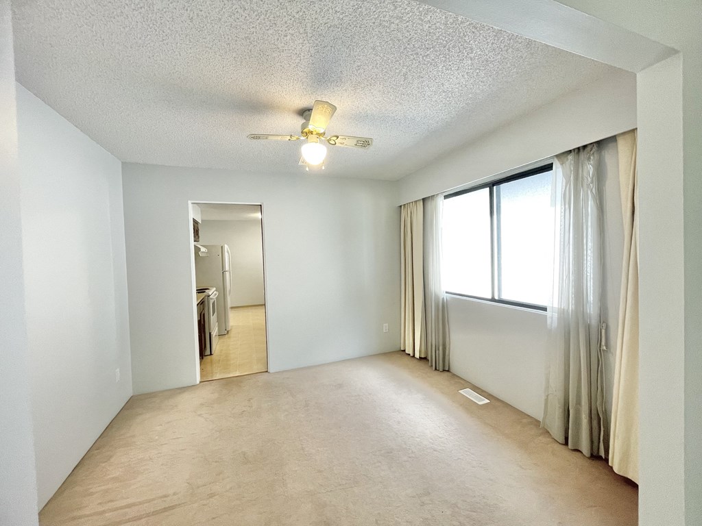 an empty living room with a ceiling fan and a window