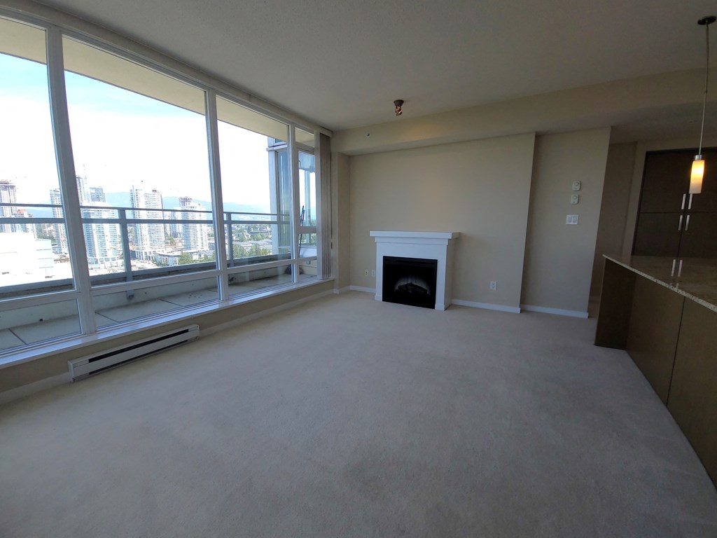an empty living room with a fireplace and large windows