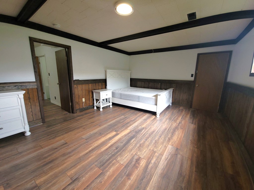 a bedroom with a bed and a wooden floor