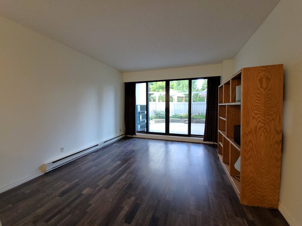 an empty living room with wood floors and a large window