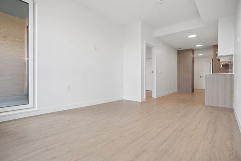 A spacious room with wooden flooring and white walls.