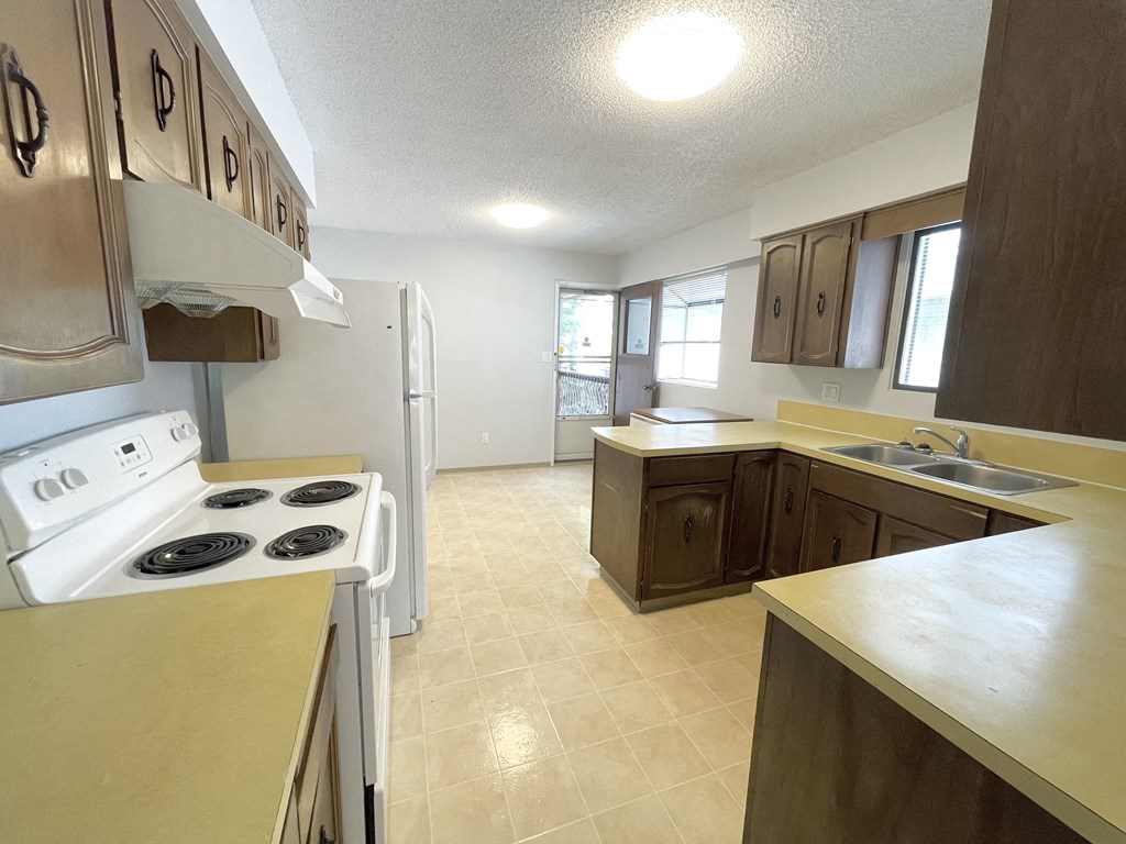 an empty kitchen with white appliances and wooden cabinets