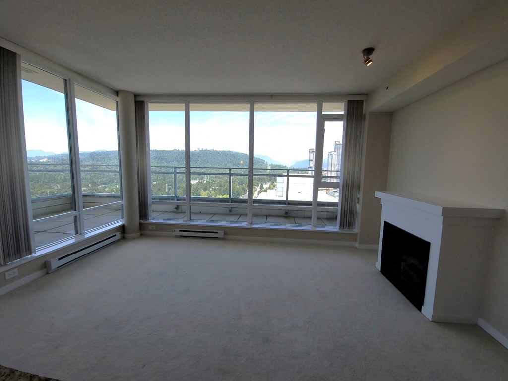 an empty living room with large windows and a fireplace