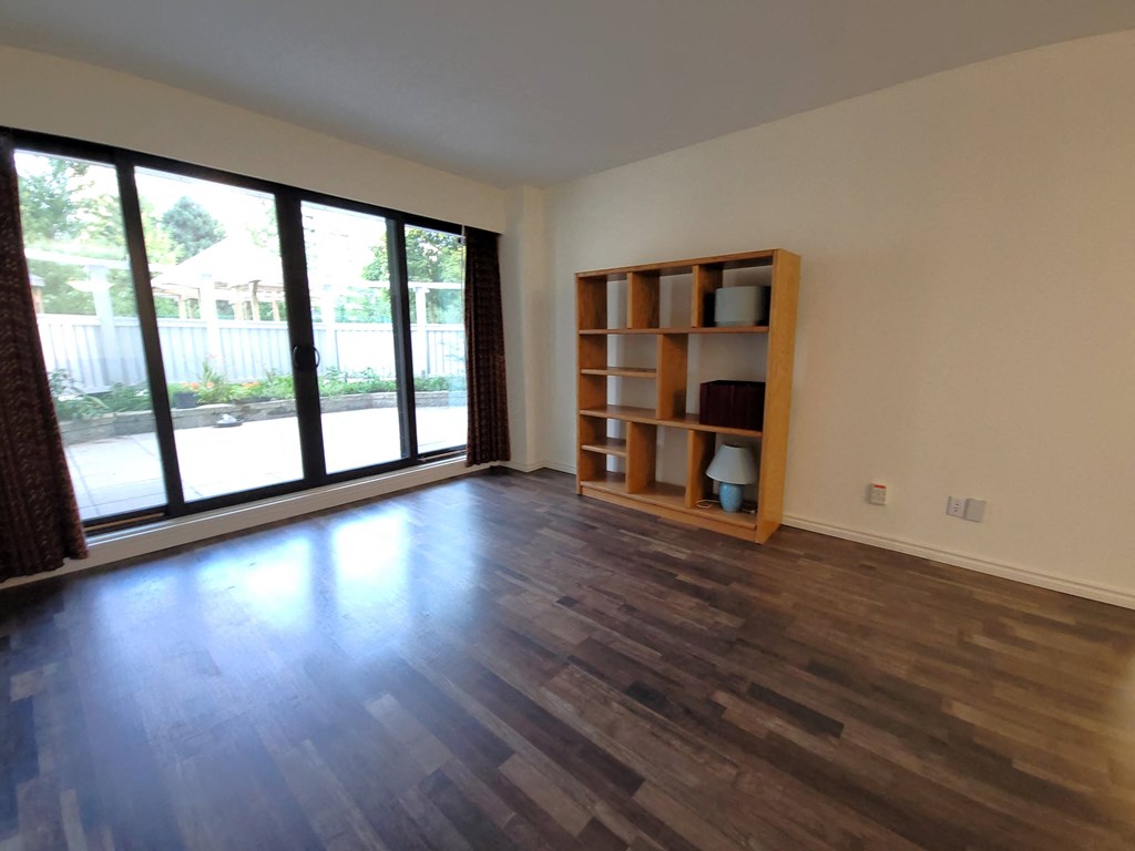 an empty living room with wood floors and a large window