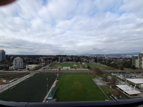 A view from an airplane window of a green soccer field and buildings in the distance.