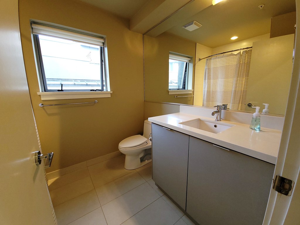 A bathroom with a toilet, sink, and window.