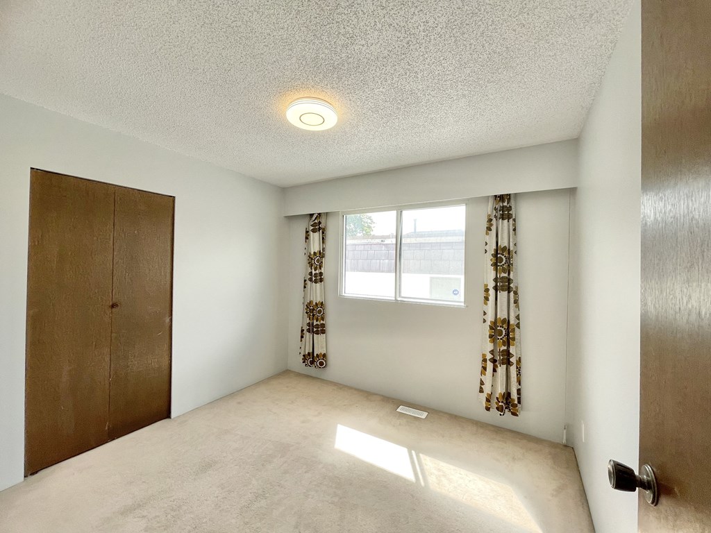 an empty room with a door and a window with curtains