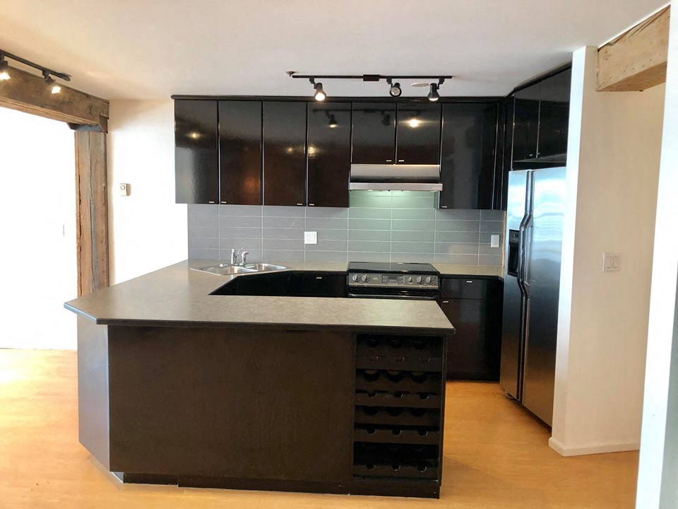 an empty kitchen with black appliances and black cabinets