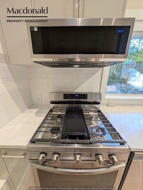 A modern kitchen with a stove top oven and microwave above it.