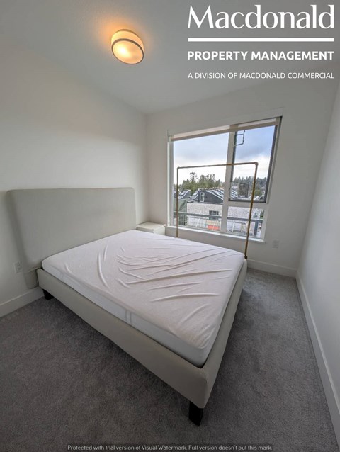 A MacDonald Property Management bedroom with a large window.