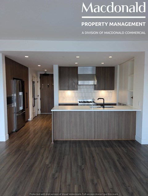 A modern kitchen with wooden floors and stainless steel appliances.