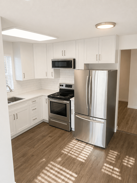 A kitchen with a refrigerator, oven, and microwave.