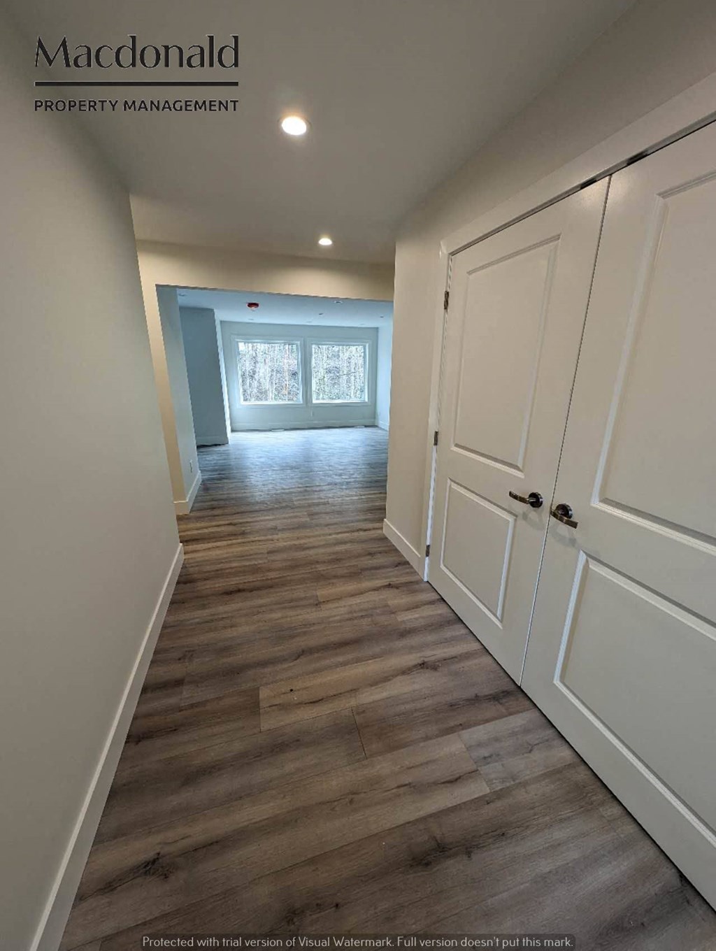 a hallway with white closets and a wood floor