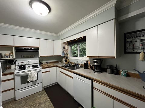 A kitchen with white cabinets and a white stove top oven.