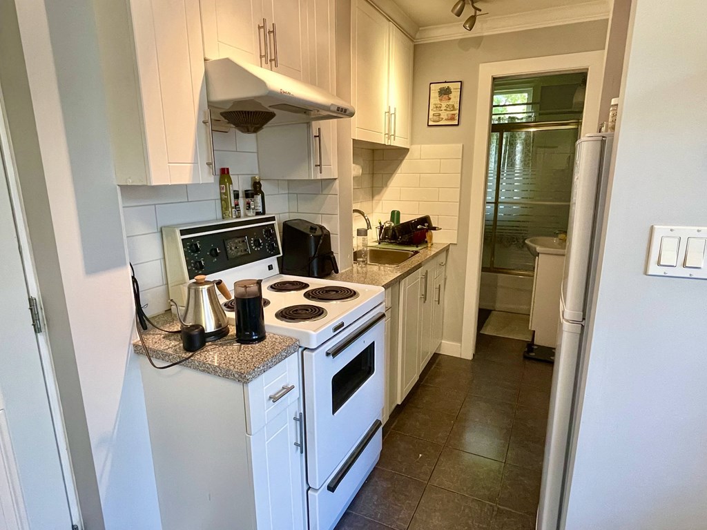 a small kitchen with white cabinets and a white stove