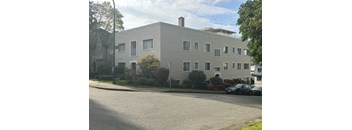 A grey building with a tree in front of it.