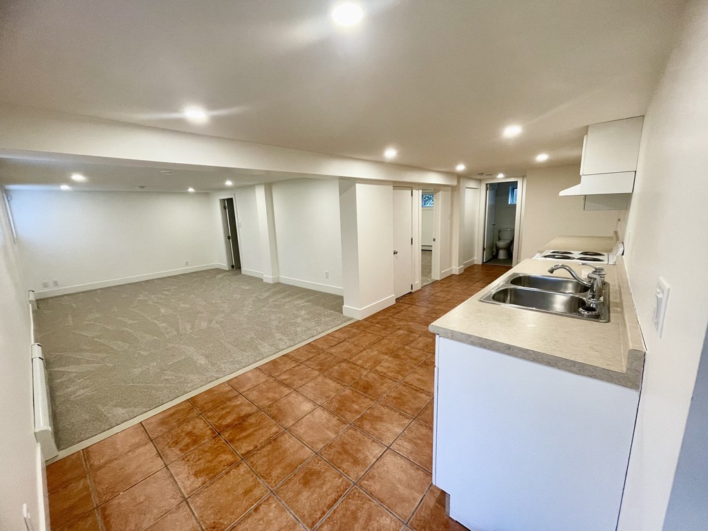 an empty living room with a kitchen and a sink