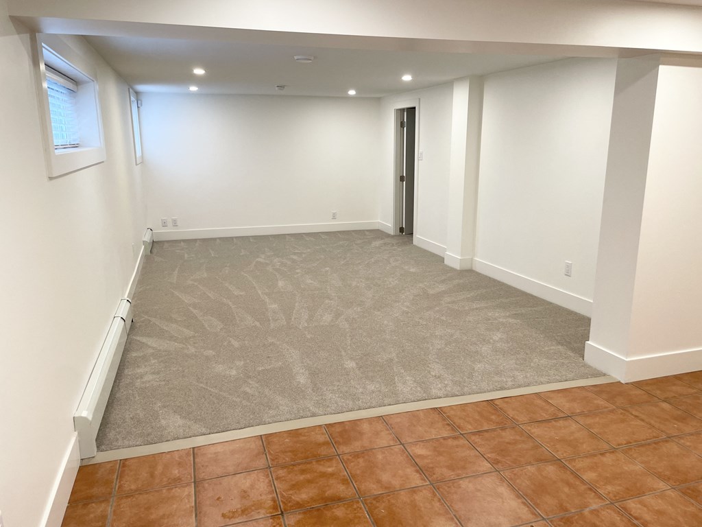 an empty living room with a tiled floor and white walls