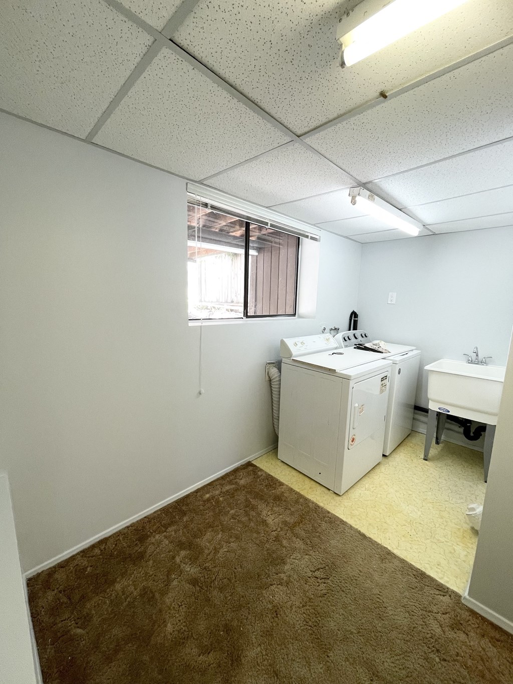 a utility room with a washer and dryer and a sink and a window