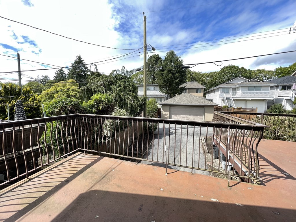 a balcony with a metal railing and a house in the background
