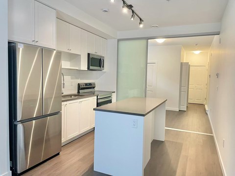A kitchen with white cabinets and a stainless steel refrigerator.