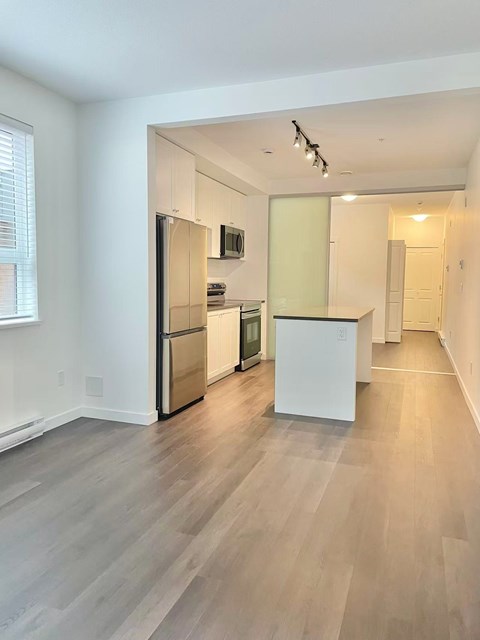 A kitchen with a white refrigerator and a white island.