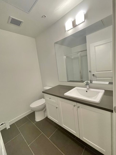 A bathroom with a toilet, sink, and mirror.