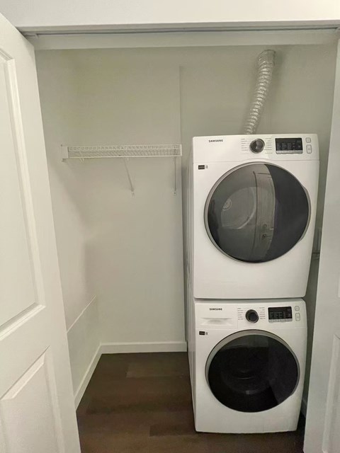 A white dryer is on top of a white washer in a small laundry room.