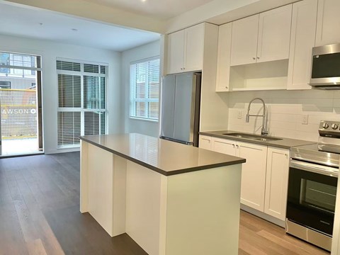 A kitchen with white cabinets and a black countertop.